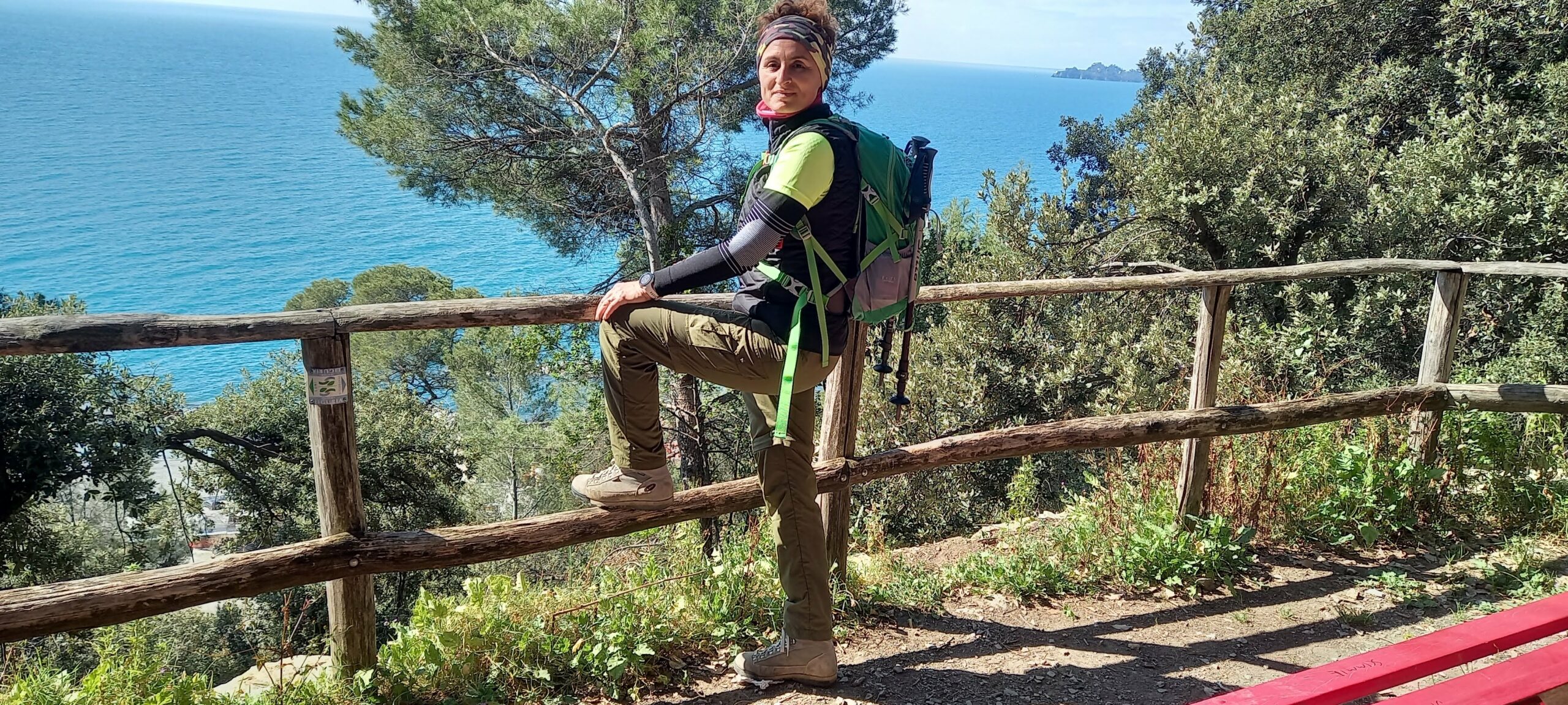 Una donna vestita da trekking in un sentiero con sfondo il mare, migliori consigli per trekking in autunno