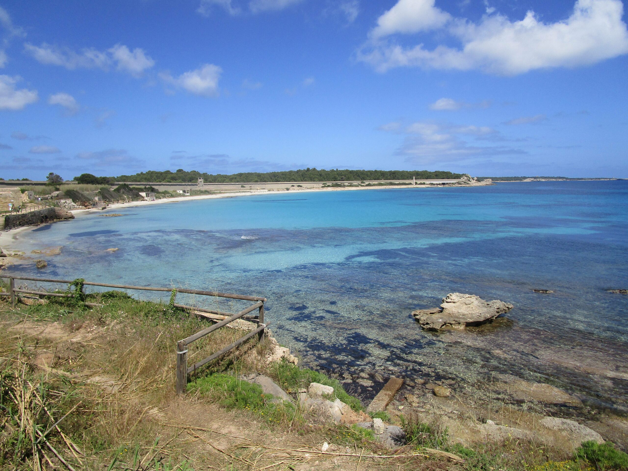 mare cristallino con rocce e alla lontana una bellissima spiaggia. I migliori consigli di trekking