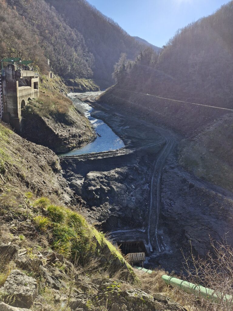 Vista di un lago quasi secco con lavori in corso. I migliori percorsi di trekking