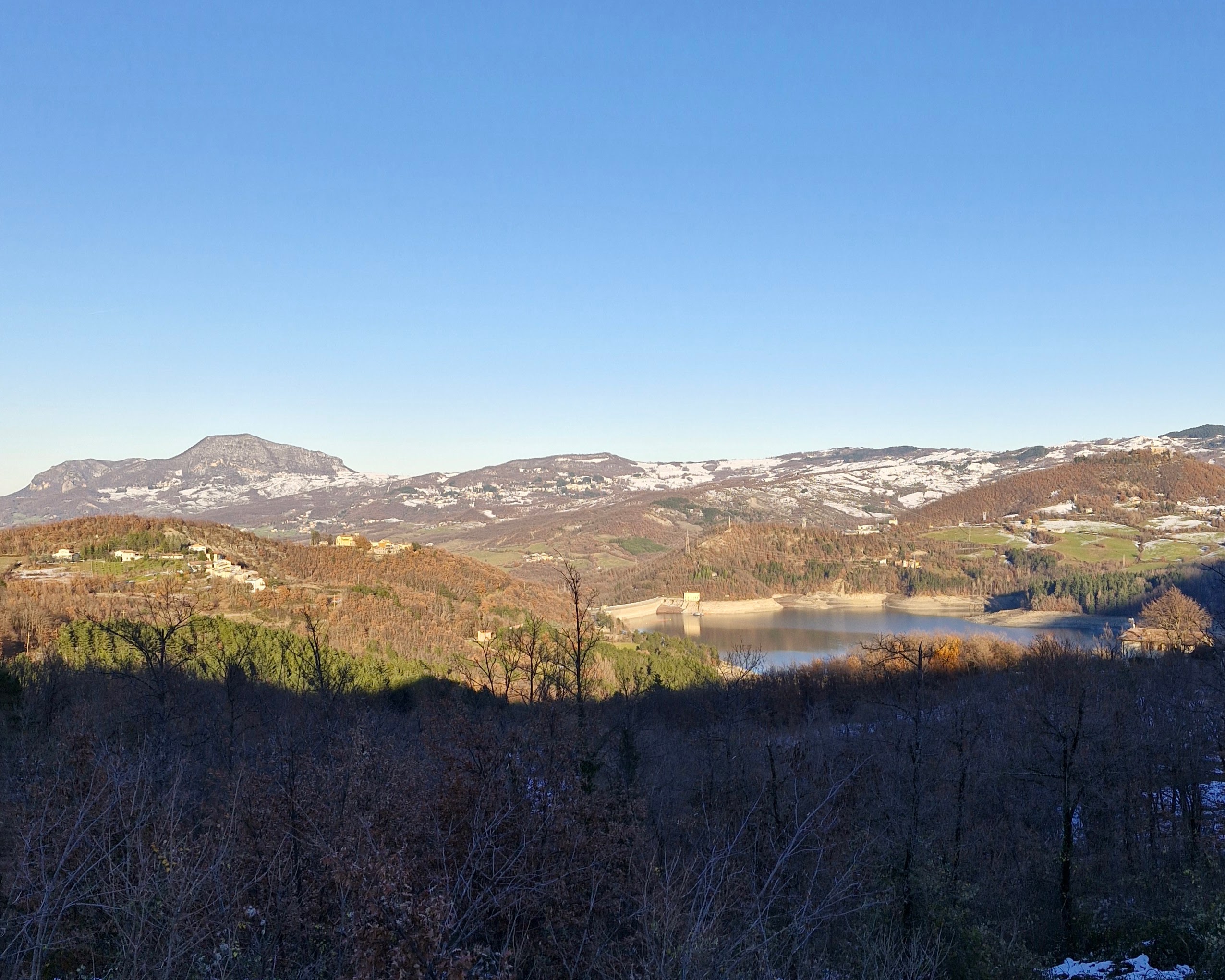 Vista panoramica di luogo montano con lago in lontananza. Un pò di neve da luce al paesaggio. I migliori consigli di trekking