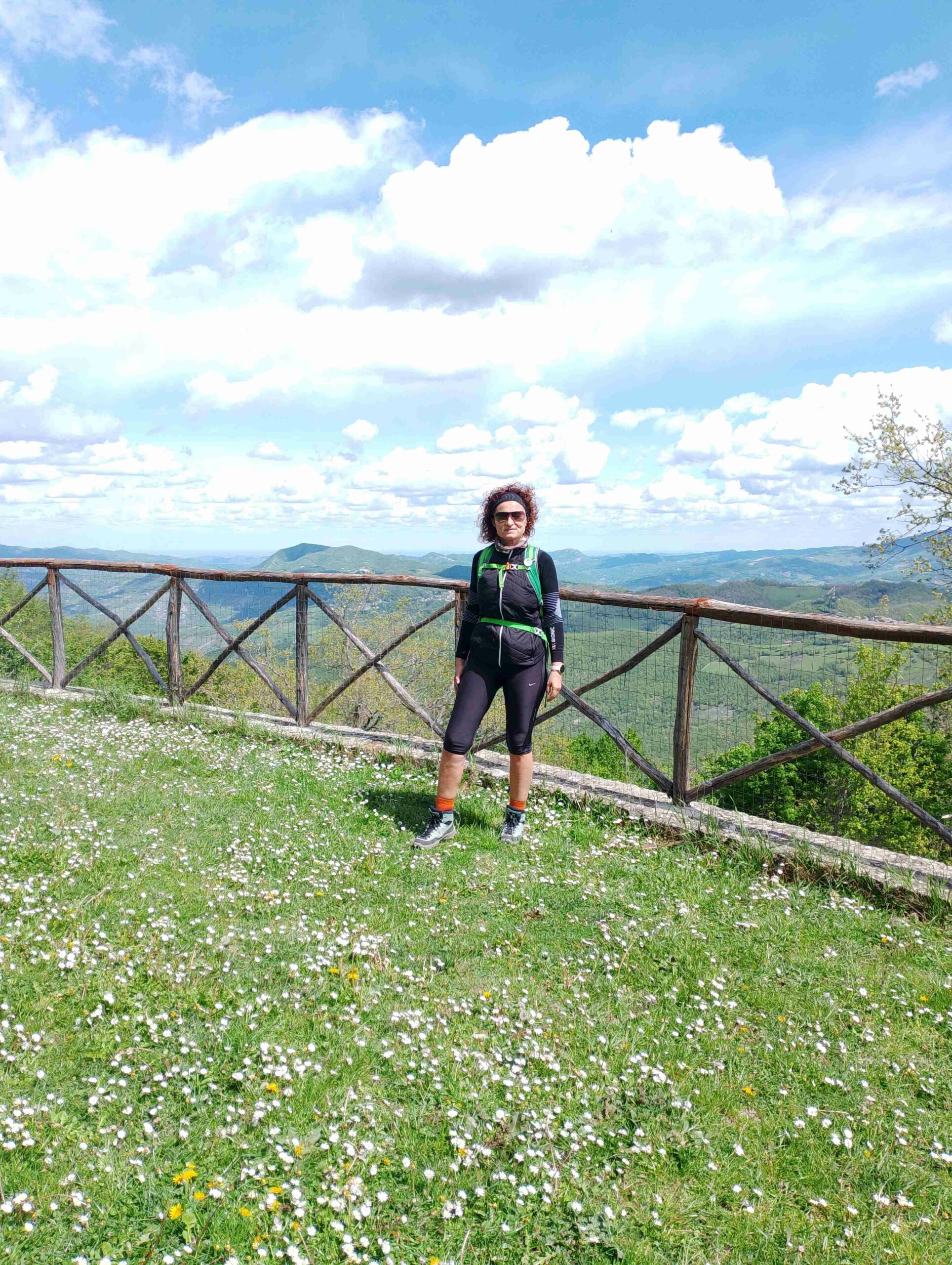 Una donna vestita da trekking in punto panoramico su un balcone montano. I migliori percorsi di trekking