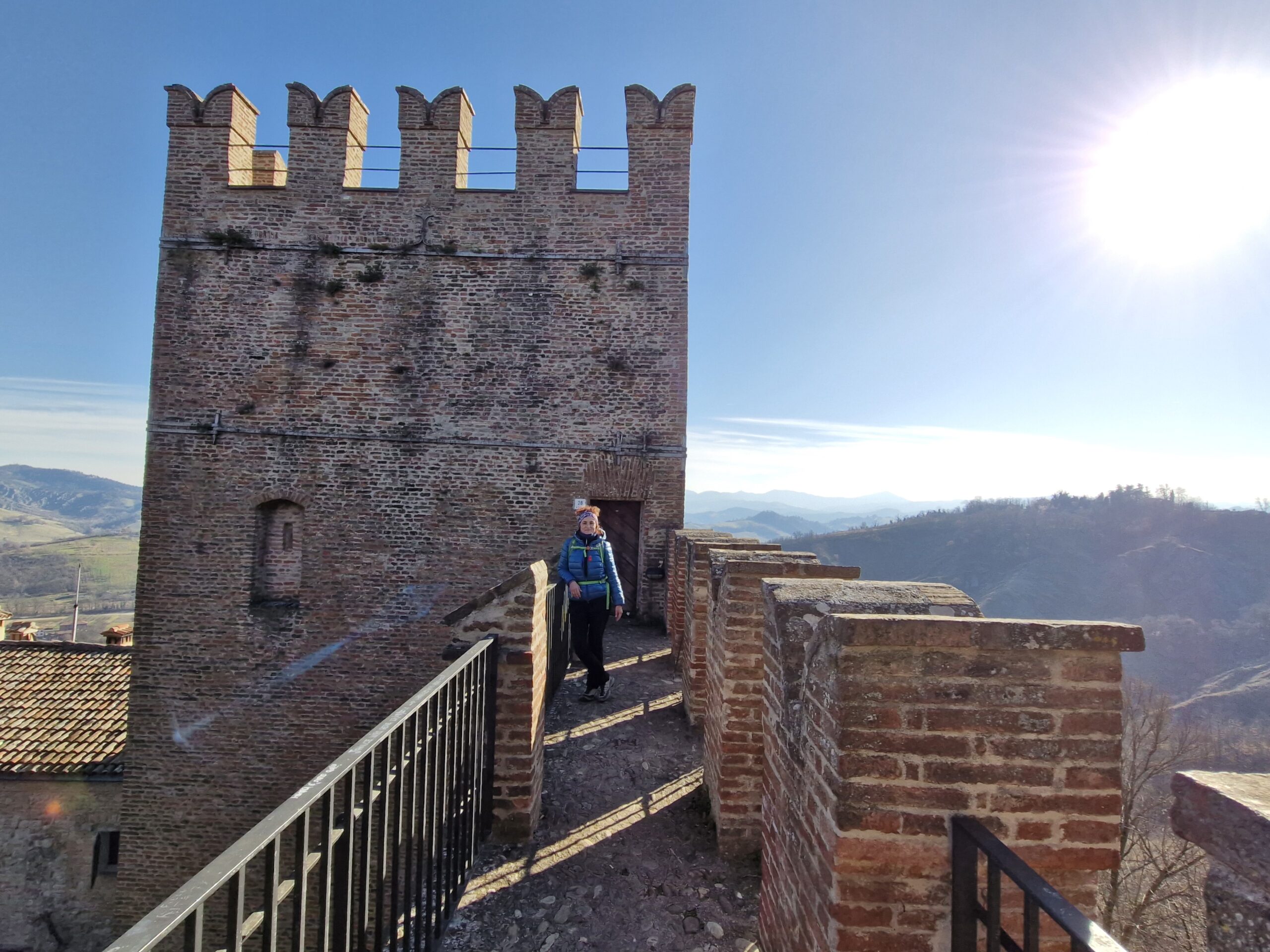 Donna vestita da trekking davanti alla torre di un castello