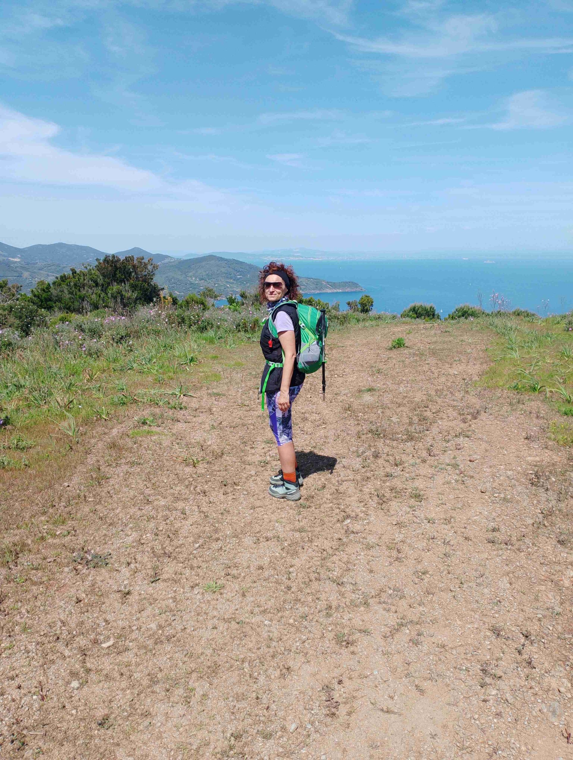 Donna vestita da trekking in sentiero con sfondo panorama di mare. I migliori percorsi di trekking