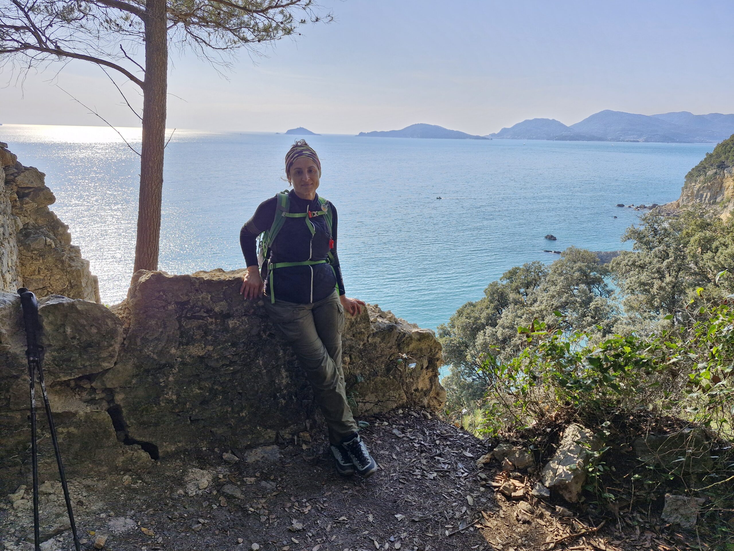 Donna vestita da trekking in sentiero roccioso con vista panoramica sul mare per i migliori consigli di percorsi trekking